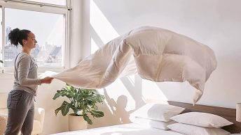 vrouw maakt bed op; dekbed in de lucht uniek